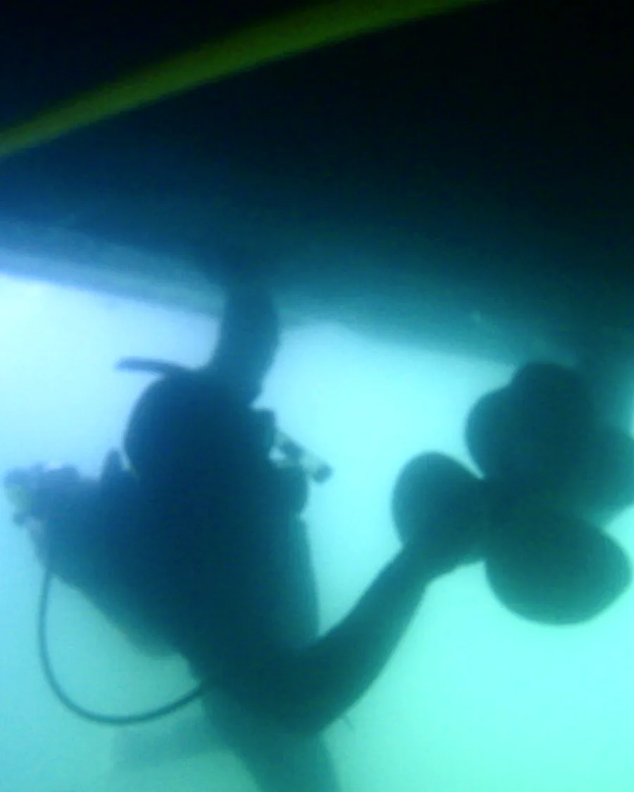 Diver near propeller and running gear underwater